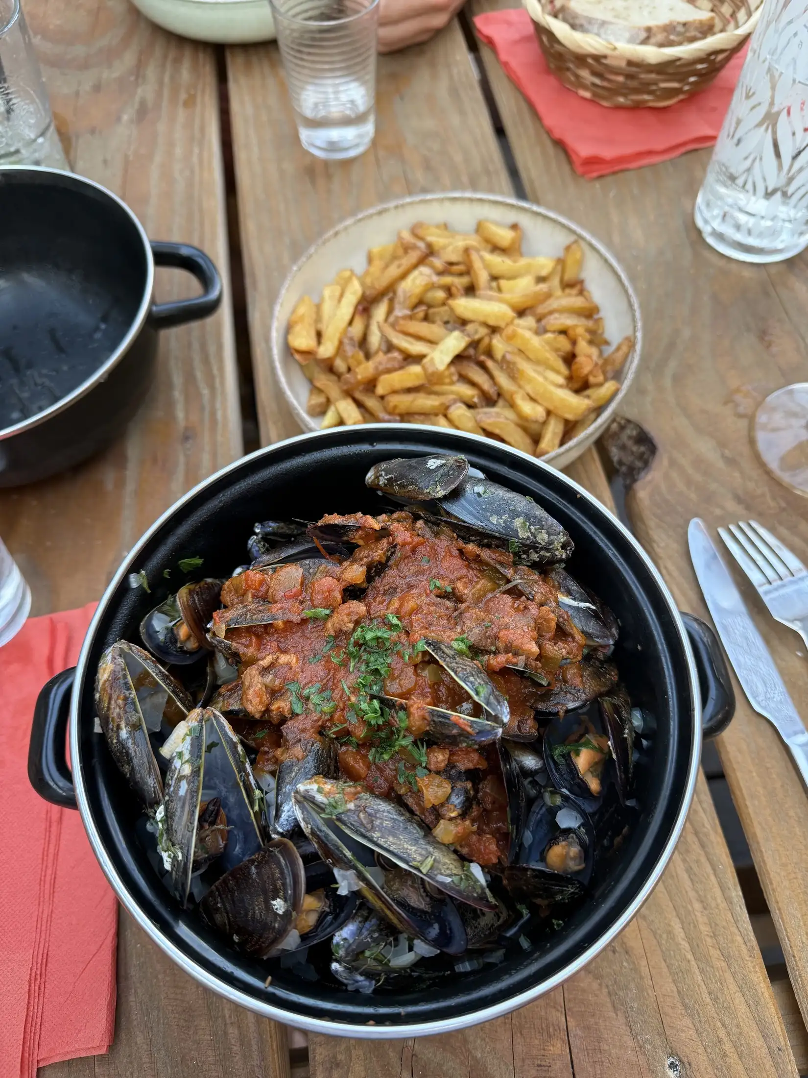 Casserole de moules en sauce tomate, servie avec des frites