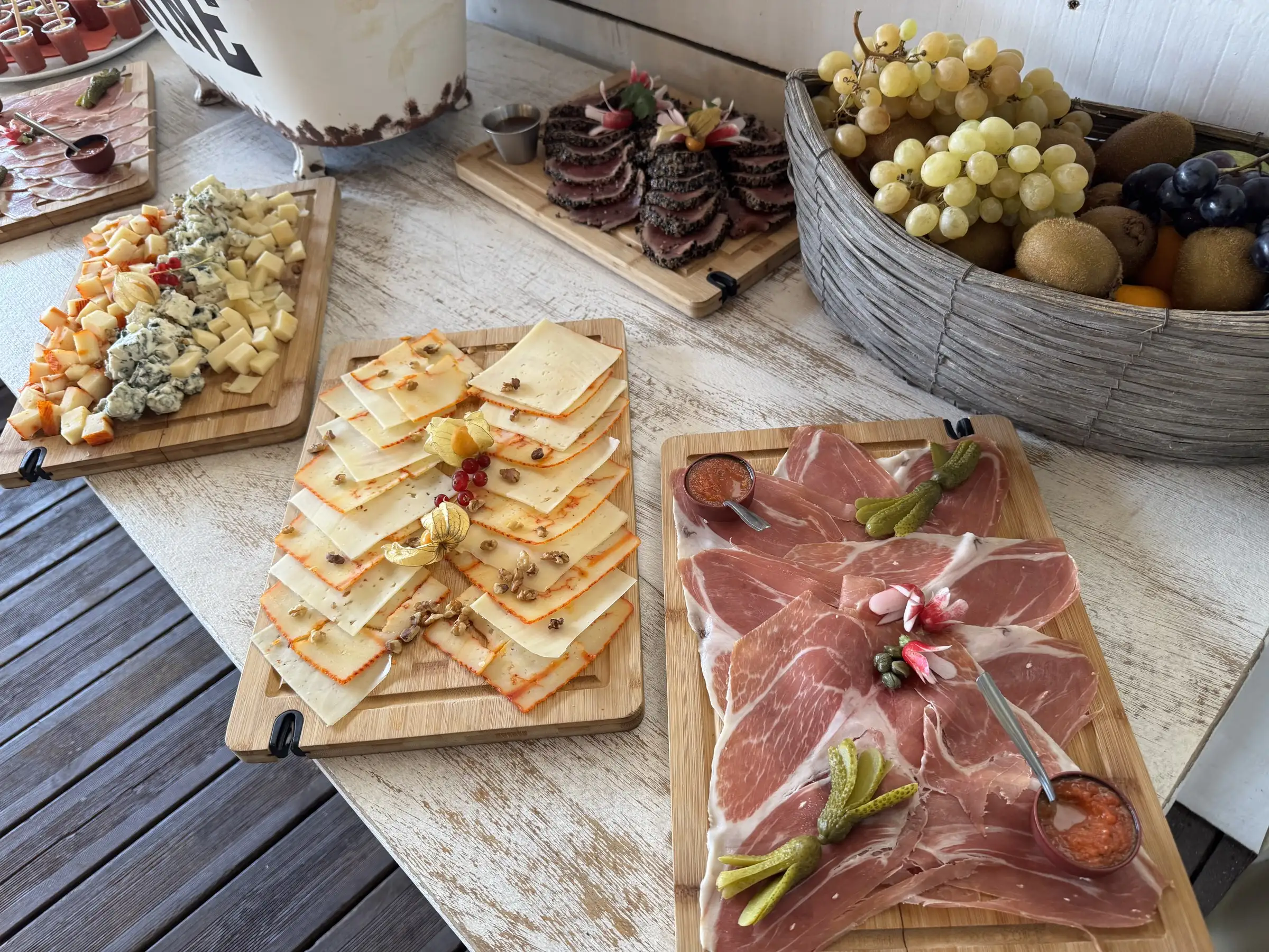 Planches de charcuterie, fromages et fruits dressées sur une table en bois