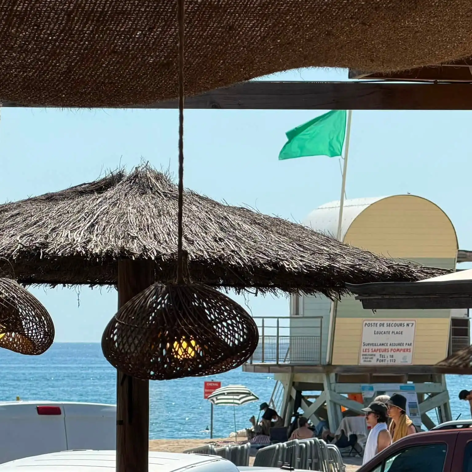 Les parasols en paille de la plage, drapeau vert et poste de secours