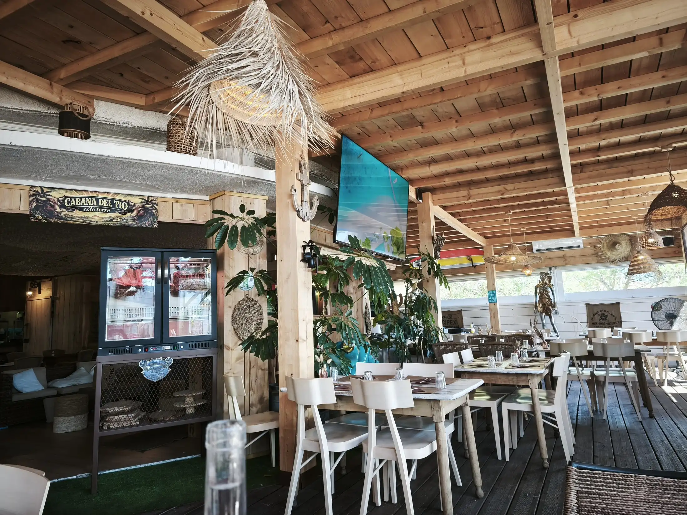 La salle couverte : tables et chaises en bois clair sous la charpente